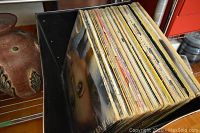 Overview of box filled with LP vinyl records showing a variety of album covers stacked vertically.