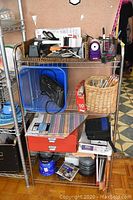 Full view of metal shelving unit loaded with various office supplies including calculators, scissors, pen holders, files, and containers