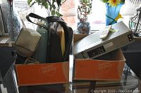 Two boxes containing various items including the typewriters, VHS/DVD player and camera tripod.