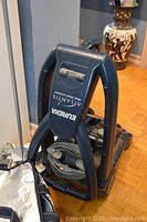 Front angle view showing the top handle, brand name, and hose wrapped around the base.