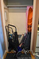 View of the closet space containing several rolled floor mats and three collapsible shopping buggies with visible signs of wear.