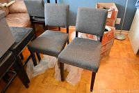 Two grey upholstered chairs front view against blue wall, showing overall style and condition