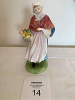 Front view of the Royal Doulton Market Day figurine holding a white goose and a basket of flowers.