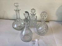 Front view of 4 vintage glass decanters showing two hand blown and two cut crystal decanters with their stoppers in place.