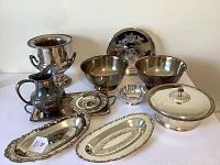 Full view of the collection showing all silver plate items arranged on a white surface including bowls, trays, bucket, and pitcher.