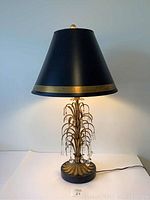 Full view of the Italian Florentine gold leaf table lamp with black and gold trimmed shade.