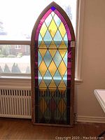 Front view of full Gothic stained glass window against radiator and window