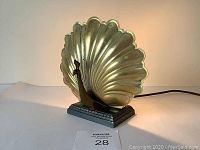 Front view of the brass peacock lamp showing the detailed fanned tail and black base.