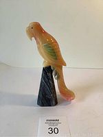Front and side view of deco marble parrot figurine on dark marble obelisk base with auction lot card labeled 30