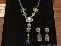 Full view of necklace and earrings set displayed in original black box, showing blue rhinestones and gold-tone settings.