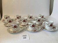 Full set of 10 Susie Cooper demitasse cups and saucers arranged on white background for display.