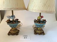 Pair of tole floral table lamps with shades, showing front and top floral decoration, placed on white background