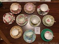 Top-down view of all 10 cups and saucers showing patterns and arrangement