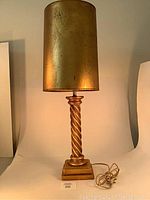 Full view of the lamp showing the gold barley twist column and gold cylindrical shade.
