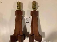 Front view of pair of Mid-Century Modern teak lamps showing geometric wooden bases and brass bulb sockets.