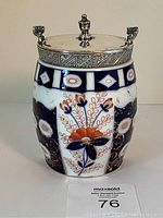 Front view of Imari porcelain biscuit barrel showing blue, orange, and gold floral designs and silver lid.