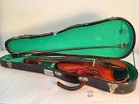 Opened case showing violin inside with green lining and black exterior case