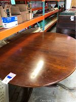 Full view of round mahogany tabletop in warehouse setting