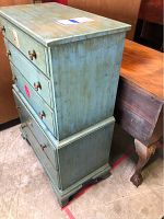 Side view of light green stained wooden chest of drawers showing five drawers and bracket feet