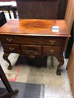 Front view of wooden chest showing three drawers, brass handles, and carved shell motif on center drawer.