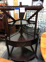 Front view of the wooden corner shelf showing the scalloped top edge, drawer with metal handle, and triangular shelf design.