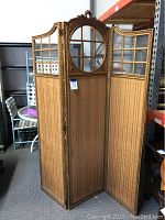 Front view of three-panel folding screen showing entire structure, gold frame, glass grid and fabric panels