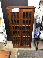 Front view of closed wooden cabinet showing dual glass-front doors with wood grill