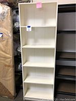 Full front view of the tall white bookcase showing all five shelves and clean white finish.