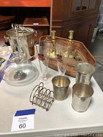 Photo showing silver cups with engravings and holder, Pilsner glasses with Princeton crests, brass candlesticks, copper tray, silver-plated ice bucket, glass plate with dome, and silver-plated toast rack.