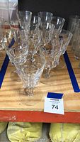 Set of 11 clear Baccarat crystal wine glasses arranged on a wooden shelf, showing their shape and design pattern.