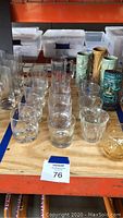 Photo of assorted clear tumblers, tiki mugs, and candle holder on wooden surface