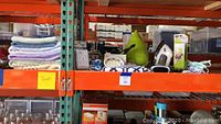 Shelving with assorted towels, hair care appliances, shower curtain, humidifier, iron, and clock radio