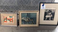 Three small framed pictures in a row: abstract, still life, figurative.