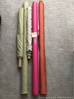 Five fabric rolls laid out showing colors and types including hot pink vinyl.