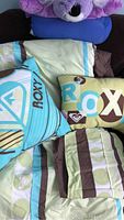 Twin bedding set with comforter, two decorative pillows and pillow sham displayed on dark surface.