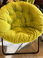 Front view of lime green cushioned chair with tufted corduroy fabric seat and backrest, black metal legs visible.