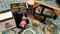 Photo showing sewing kit box, plush dog, multi-photo frame, pink laundry bag, two vases, and small photo holder on top of teal and white mandala tapestry.