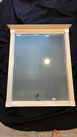 Front view of the heavy beveled mirror showing white decorative frame and beveled glass surface.