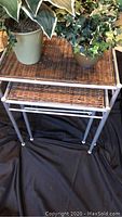 Three rattan nesting tables stacked together, each with woven rattan tops and tubular metal legs.
