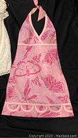 Pink Lilly Pulitzer halter dress with butterfly and floral print pattern laid on black fabric