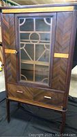 Front view of the sideboard showing single glass door with geometric wood pattern and lower drawer with handles.