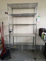 Full view of the metal wire shelving unit showing five shelves including a shelf with a white solid surface cover.