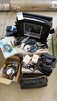Porta-Vue portable TV-DVD player in carrying case, boxed accessories, portable cassette radio player, binoculars, headphone sets, and cellphone cases