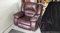 Leather-look recliner chair against a light wall, showing side and front view with visible wear and marks.