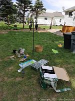 Wide shot of garden decor items including resin cat in log, gnome, frogs, butterfly stakes, and solar peacock stake light on grass.