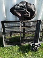 Folded ramp platform leaning against exterior wall with branded fabric cover draped over top