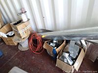 Overview image showing three spools of electric wire, orange extension cord, two boxes of galvanized air duct components, and a rolled flexible duct lining or insulation sheet.