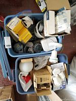 Top view of two full Rubbermaid bins with assorted electrical installation hardware including boxes, switches, and lighting fixtures