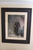 Full view of the framed Abraham Lincoln lithograph artwork hanging on a wall with visible reflections on the glass.