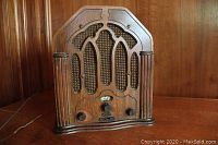 Front view showing carved wooden cathedral style case with grille and control knobs